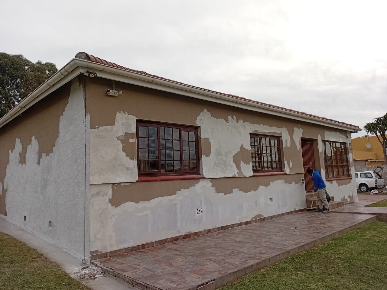 Before: House exterior in Port Elizabeth with peeling paint and exposed plaster patches needing renovation