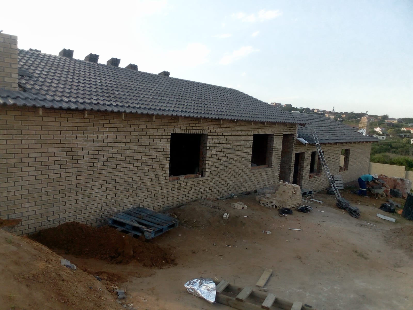 Roofing contractors Port Elizabeth — completed dark grey tiled roof on yellow brick house