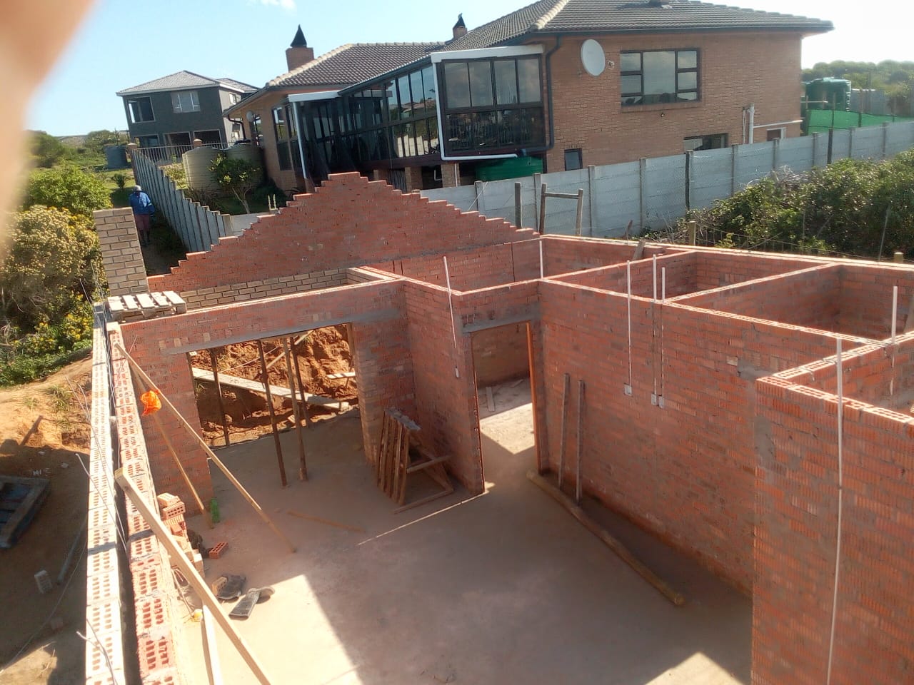 Builders in Port Elizabeth — red brick walls rising from foundation with gable end framed up, Osflex Construction
