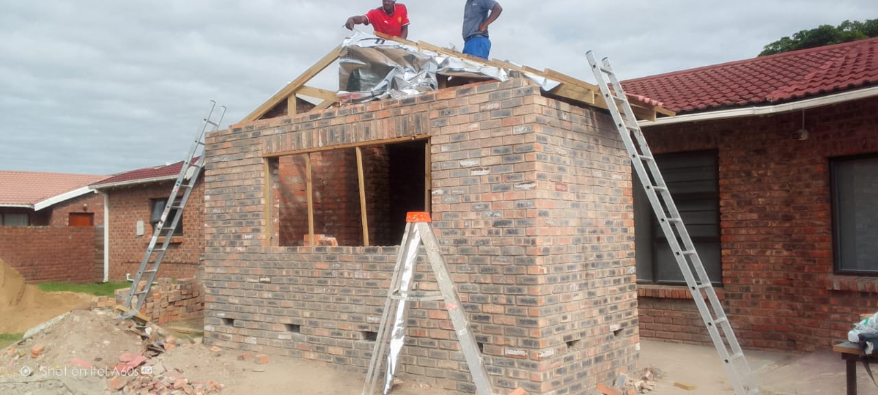 Before: Roofing contractors Port Elizabeth — workers installing timber roof trusses and foil sarking on brick extension