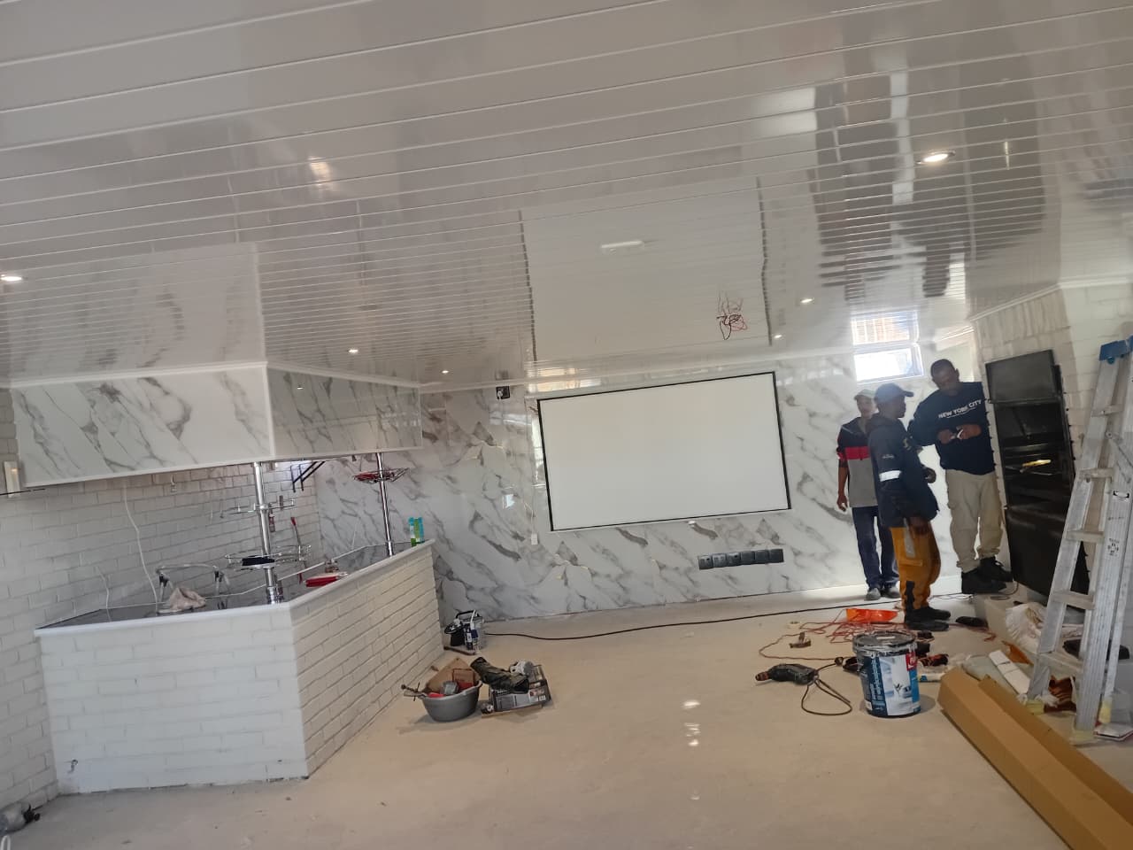 After: Completed commercial interior with glossy white PVC ceiling, cornice detailing, recessed lights and marble-effect feature wall panels